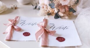 Individuell gestaltete Eheversprechen mit rosa Schleifen und Wachssiegel neben einem Brautstrauß.